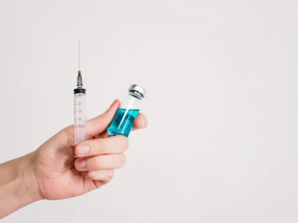 person holding syringe and vaccine bottle