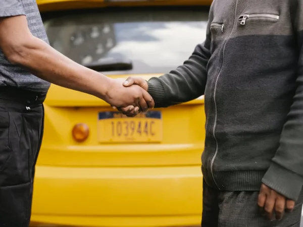 ethnic men shaking hands near taxi